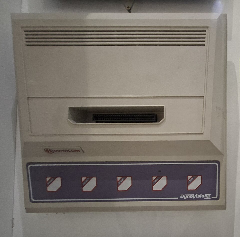Dynavision 2, console bege com painel lilás e botões Reset, Select, Start, On e Off